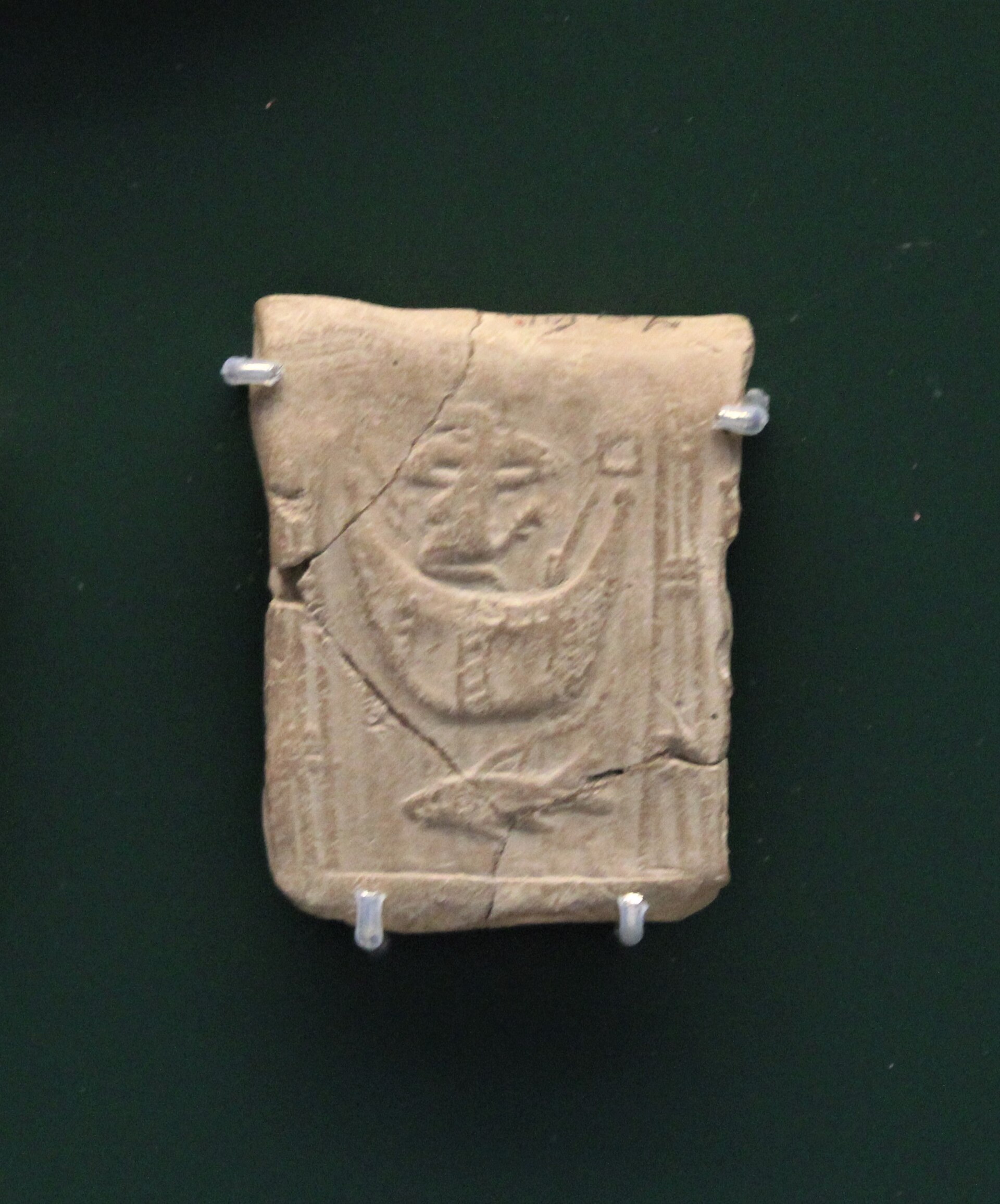 Small clay tablet with a rolled cylinder seal impression showing carved figures